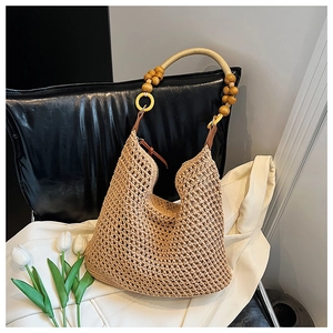 Detail of hand-woven straw tote bag with decorative wooden beads and gold rings handles