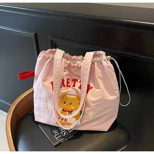 Detail view of pink nylon tote bag featuring red PRETTY text and embroidered sailor bear