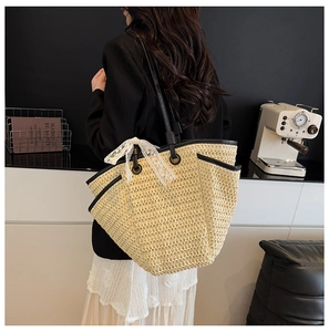 Détail du sac cabas en paille avec bordure en cuir noir et nœud en dentelle blanche