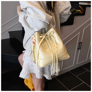 Detail of yellow patent leather bucket backpack with drawstring and cute pig charm