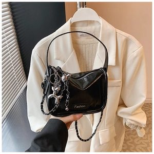 Detail of glossy black patent leather bag featuring a chic silver balloon dog charm