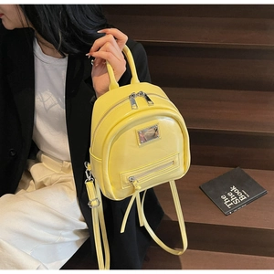 Detail of a bright yellow PU leather mini backpack with metal dual zippers and top handle