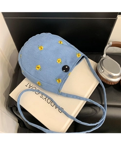 Détail du sac en toile bleue avec broderie florale jaune et boucle ronde noire