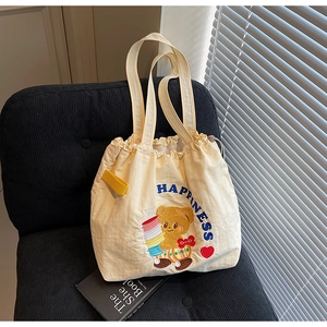 Detail of cute bear embroidery and Happiness text on a cream canvas tote bag