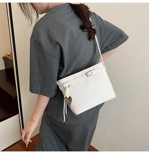 White lychee grain bucket bag with belt buckle detail and leopard print heart charm