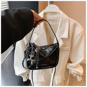 Detail of black patent leather crossbody bag with silver chain and balloon dog charm