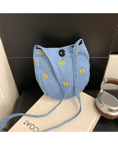 Détail du petit sac bandoulière en denim bleu clair avec fleur brodée et bouton pression