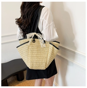 Détail du sac cabas en paille tissée avec nœud en dentelle blanche et anses noires