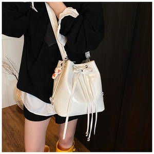 Detail of white patent leather bucket bag with drawstring closure and cute bunny charm