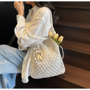 Detail of white hollow woven tote bag with chunky rope shoulder strap and pearl charm