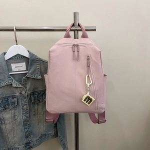 Detailed close-up of pink nylon backpack featuring vertical zip pockets and m-logo charm