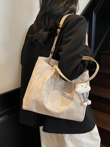 Grand sac cabas beige en jacquard fleuri avec bandoulière en cuir porté à l'épaule