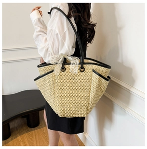 Détail du sac cabas en paille tissée avec bordure noire et décoration en dentelle