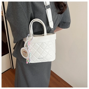Detail showing the white quilted texture and colorful capybara charm on the bucket bag