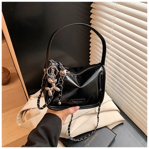Detail of black patent leather crossbody bag with silver chain and balloon dog charm