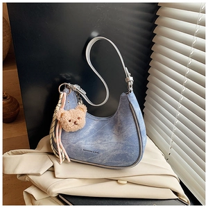 Detail of light blue denim crescent bag with silver trim, teddy charm and silk scarf