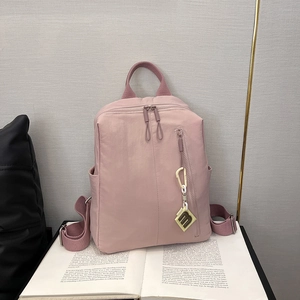 Close-up of pink nylon backpack with vertical zipper and decorative letter pendant