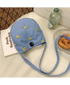 Détail du sac bandoulière en denim bleu clair avec broderie de fleurs jaunes et bouton
