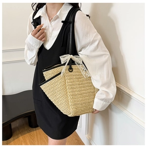 Détail d'un sac cabas en paille avec anses en cuir noir et nœud en dentelle blanche