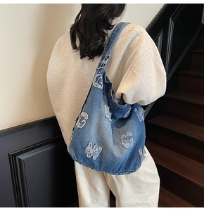 Detail showing the large capacity washed denim tote bag with letter patches on model
