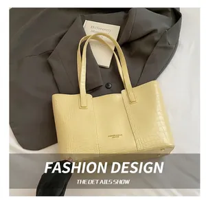 Detail view of the crocodile-textured butter yellow tote bag with metallic base studs