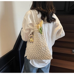 Detailed close-up of a hollow-out woven tote bag with a cute doll pendant and tulip decor