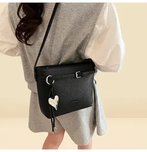 Detail of black lychee grain bucket bag featuring a silver heart charm and leather strap