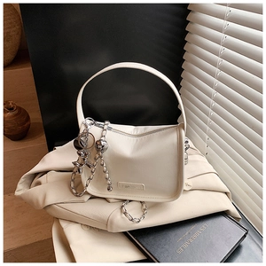Detail of white leather shoulder bag with silver chain strap and metal bear charm