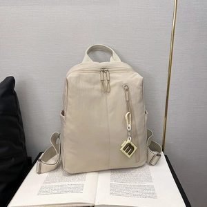 Detailed view of beige nylon backpack texture with m-pendant and adjustable straps