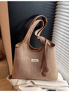 Stroh-Tragetasche mit braunem Lederbesatz und COIN'DA2-Markenschild im minimalistischen Stil