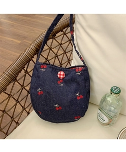 Gros plan du sac en jean avec broderie cerise et bouton à carreaux rouges et blancs