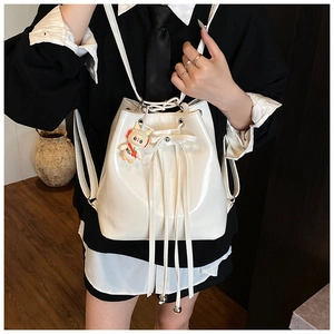 Detail of a shiny white bucket backpack with drawstring and cute rabbit keychain accessory