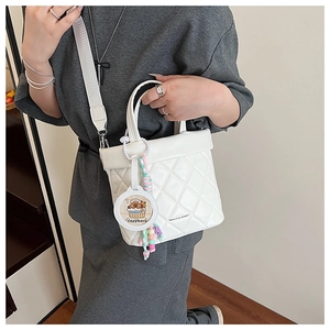 Close-up of white quilted bucket bag with a cute Capybara charm and wide strap