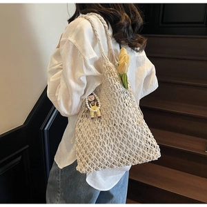 Close-up of beige macramé woven tote bag with a cartoon pendant and yellow tulip flower