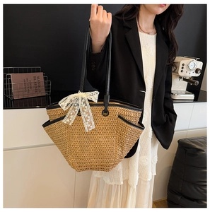 Détail du sac cabas en paille tissée avec anses en cuir noir et nœud en dentelle blanche