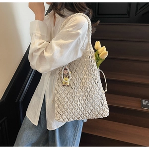 Detail of white macrame woven tote bag featuring a cute doll pendant and drawstring closure