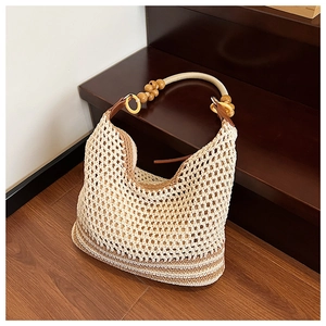 Detail of beige crochet beach bag with wooden bead handles on a wooden staircase