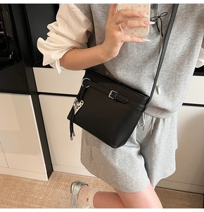 Detail of black lychee grain bucket bag featuring a silver heart charm and belt buckle strap