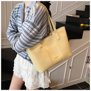 Fashionable light yellow crocodile pattern tote bag shown over a model's shoulder