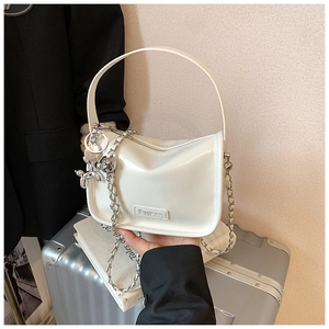 Detail of white PU leather crossbody bag with silver chain and metal dog charm pendant