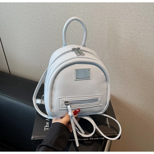 Detail view of mini light blue leather backpack with metal plaque and zipper pockets