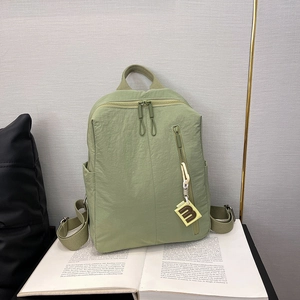 Close-up of light green nylon backpack with B-letter tag on English books background