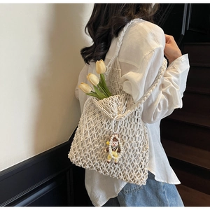 Detail of white handmade bohemian woven tote bag with hollow grid texture and charm