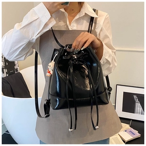 Detail of glossy black patent leather bucket bag with drawstring and rabbit pendant