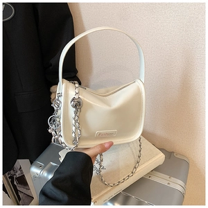 Detail of white crescent shoulder bag with silver chain charms and Fashion logo label