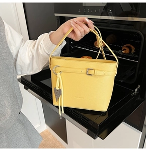 Detail of yellow lychee pattern bucket bag with metal buckle and heart pendant in creative setting