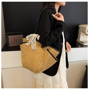 Détail du sac cabas en paille avec nœud en dentelle blanche et anses noires