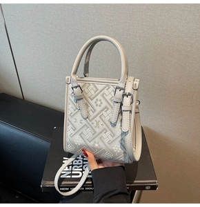 Détails de broderie géométrique grise et de fleurs sur un sac à bandoulière rigide