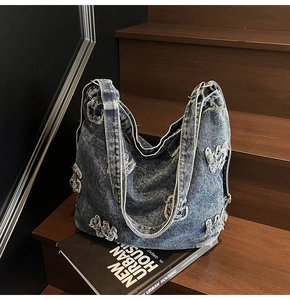 Detail showing distressed star patches and washed denim texture of a vintage hobo bag
