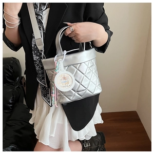Close-up of silver quilted bucket bag with a wide strap and cute capybara charm accessory